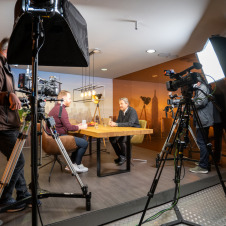 Zwei Männer diskutieren an einem Tisch beim digitalen Format Studio X