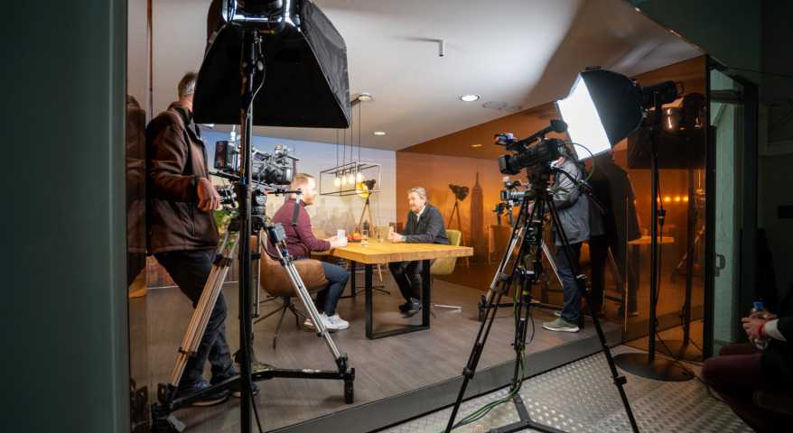 Zwei Männer diskutieren an einem Tisch beim digitalen Format Studio X
