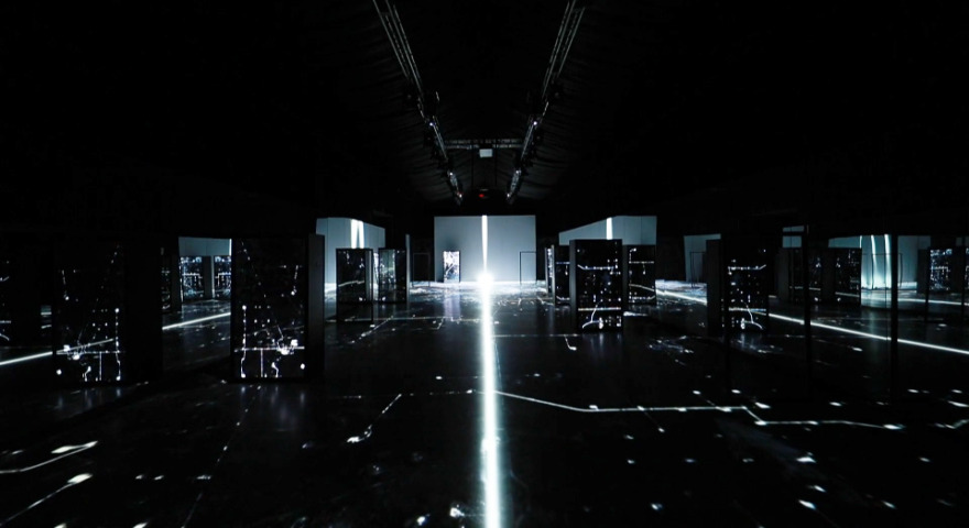 Dunkler Raum, der von einer multimedialen Installation inszeniert wird.